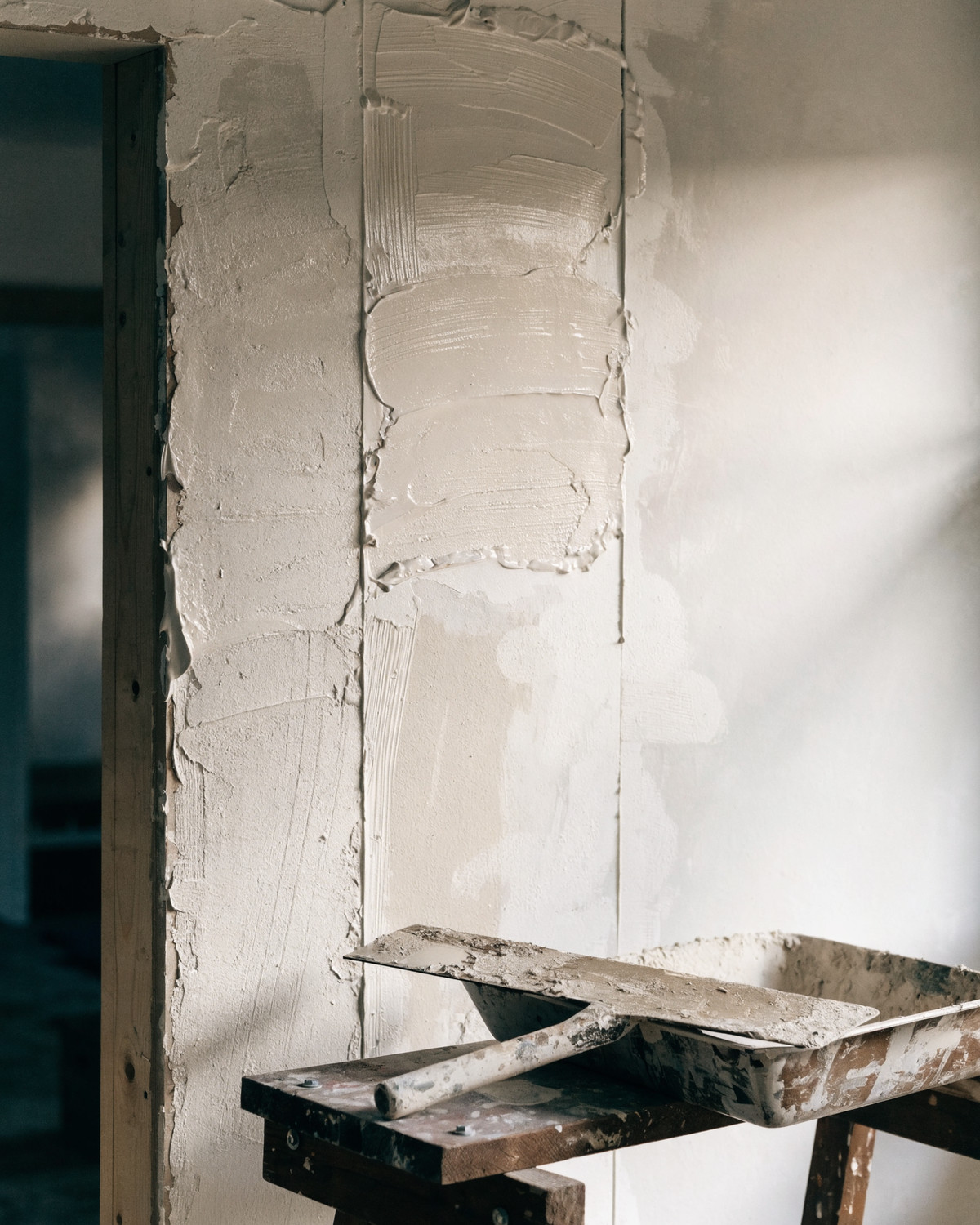 Frisch verspachtelte Innenwand mit Spachtel und Werkzeug auf einem Bock